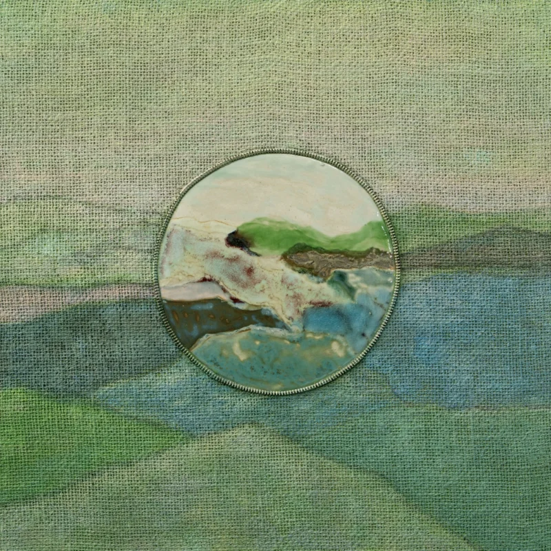 round ceramic inset within green-toned textile landscape, soft gradients, mixed media abstraction 緑系の布地に円形陶片を配置した作品、柔らかなグラデーション、抽象表現