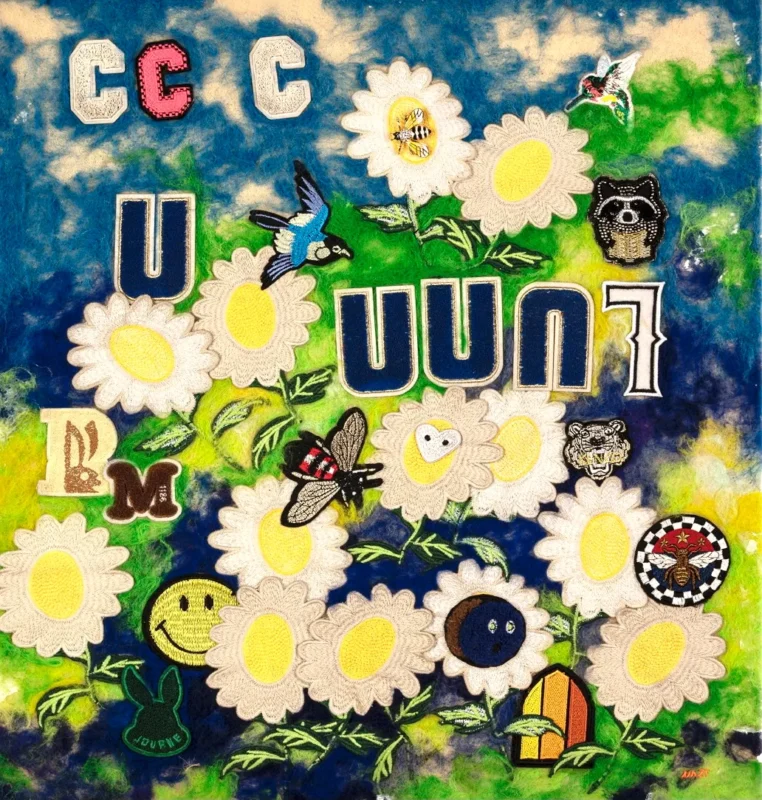 Colorful mixed-media artwork featuring white flowers, birds, butterflies, smiling faces, letters, and decorative motifs arranged across a blue and green background.