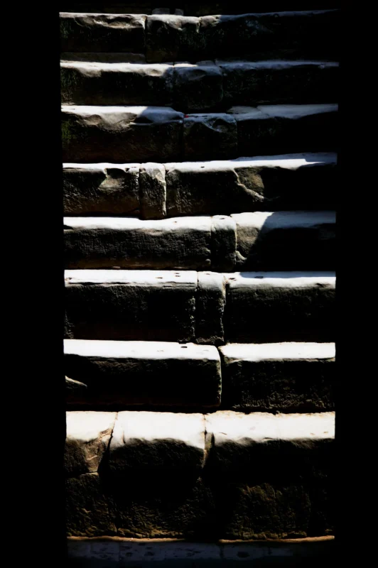 Ancient stone steps illuminated by dramatic sunlight, creating a stark contrast between light and shadow.