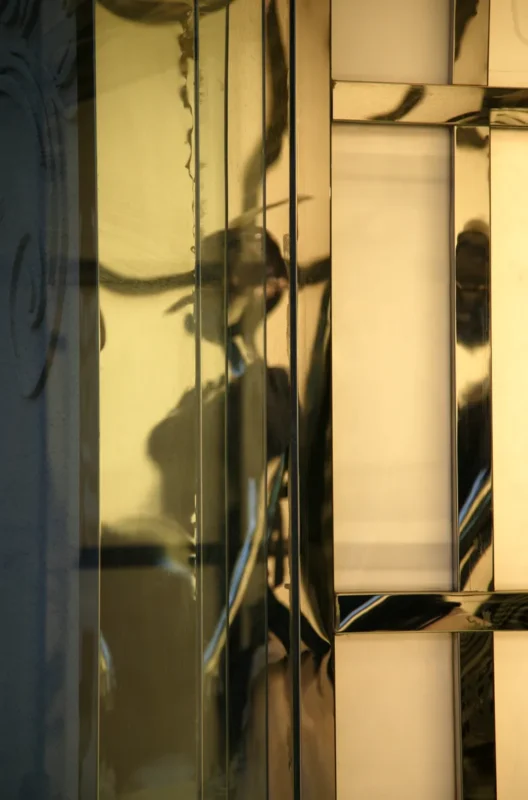 A human-shaped silhouette cast by warm evening light appears on a wall, creating a fleeting image of presence.
