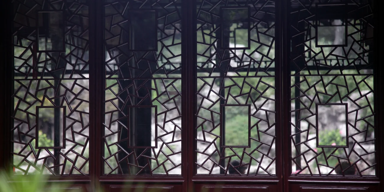 Traditional lattice windows filtering light and shadow in a Jiangnan garden pavilion.