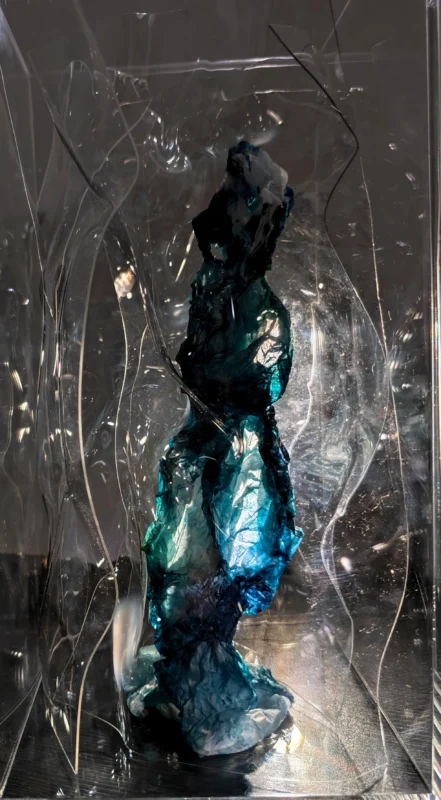 Paper sculpture Memory, featuring a suspended blue human-like form enclosed within a transparent acrylic structure.