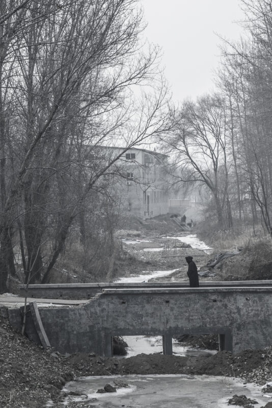 A solitary figure crossing a small bridge in a winter landscape from Wang Wulong’s Receding Landscape series.